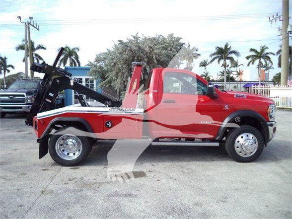 Ram 4500 tow truck side view with red cab and bed, wheel hubs visible, tow equipment in rear.