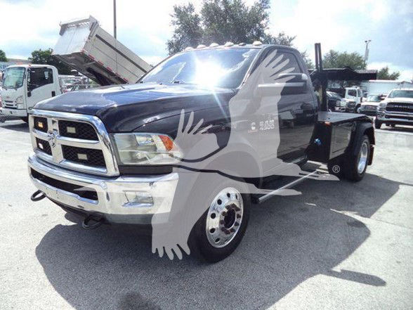 Ram 4500 tow truck cab with front chrome bumper and decal art on doors, black and silver color, visible wheel rims and dump bed in background.