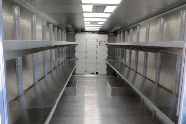 Interior cargo area of a 2015 Ford F59 step van showing metal shelving along both sides and a white rear door.