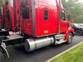 Western Star 4900 exterior cab area showing cylindrical fuel tank and red body panels.