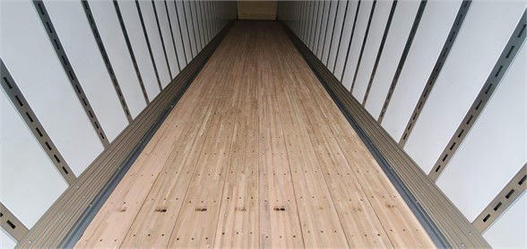 Van trailer interior with wooden floor and sidewall posts; long empty cargo area
