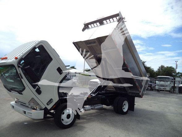 Dump truck bed raised on a Chevrolet W4500 dump truck with cab tilted forward, showing hydraulic components and dump body.
