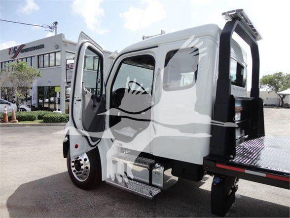 Freightliner Business Class M2 106 truck cab with open driver door and flatbed tow equipment visible.