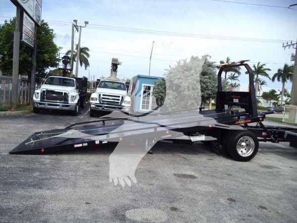 Kenworth T280 flatbed tow truck shown in inventory lot with two white trucks in background.
