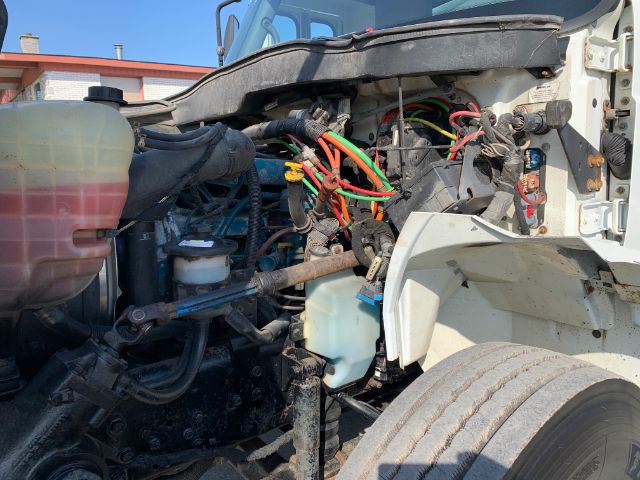 International truck engine bay showing coolant reservoir, power steering fluid reservoir, and a bundle of colored ignition wires; various hoses and components visible.