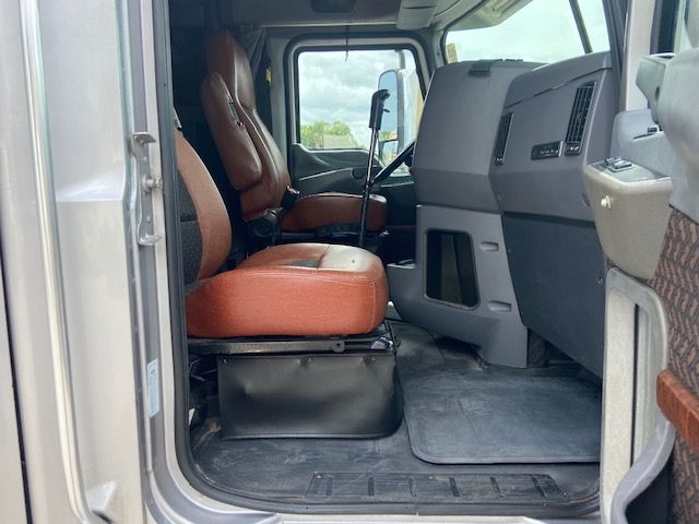 Cab interior of a Mack CXU613 truck showing orange leather seats and gray dashboard; front door open.
