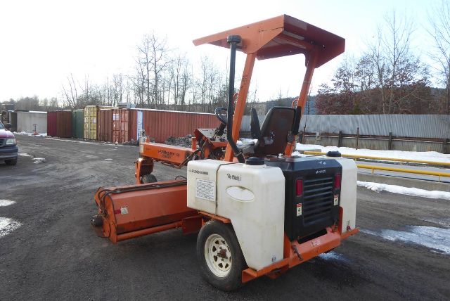 Side view of a 2012 Laymor SM300 small road roller with white and orange body, operator seat, roll bar, and drum at the front, parked on a lot.