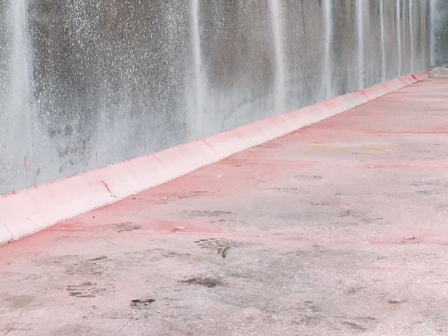 Scrap gondola trailer context image showing a concrete rooftop edge and pink curb with water spray from a wall.