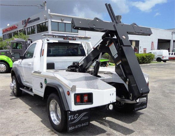 Ram 4500 SLT tow truck with a hydraulic bed and crane attachment, rear view showing service body and raised lifting apparatus.
