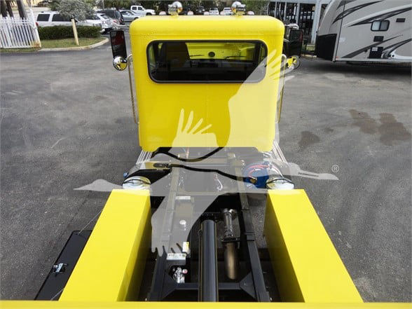 Yellow Peterbilt 337 truck cab and hitch area with exposed hitch mechanism and hydraulic lines.