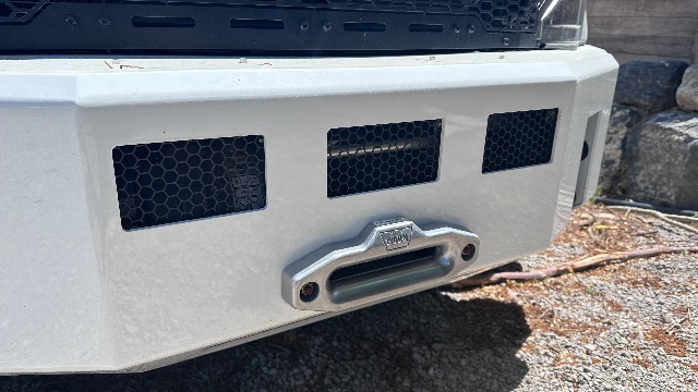 Front bumper of a 2022 Ford F-550 Lariat Cab and Chassis showing a recessed tow hook with the word 'FORD' on the hook plate and ventilated grilles.