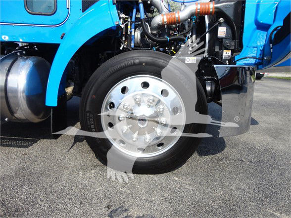 Front wheel and suspension of a blue Peterbilt truck with visible exhaust pipes and components; no legible small text captured.