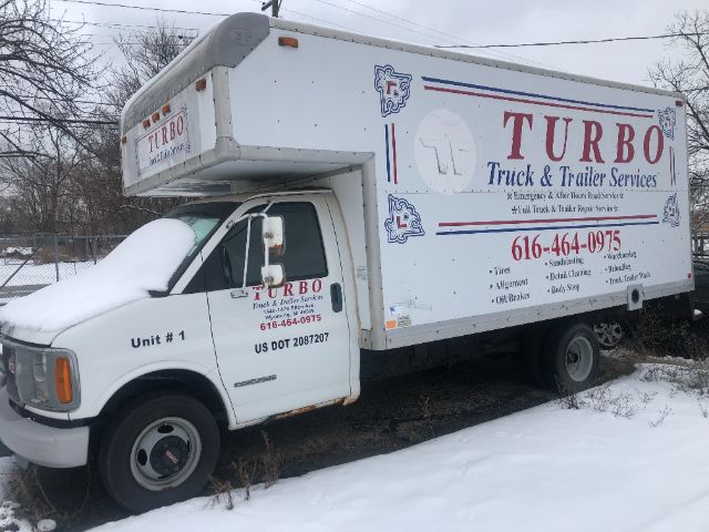 2002 GMC small box truck with large cargo box on chassis, white with Turb0 Truck & Trailer Services graphics on side, snow on cab and ground, service truck.