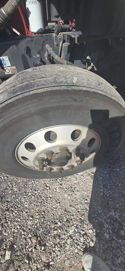 Kenworth T680 front wheel and fender area showing hub, lug nuts, and tire on a heavy truck.
