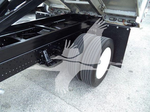 Side view of a 2019 Isuzu NPR HD truck chassis showing rear dual wheels and flatbed lift mechanism; visible frame and suspension components.