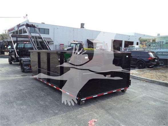 Dump truck bed with black coating and red/white reflective tape along bottom edge in a parking lot; background shows a truck and industrial buildings.