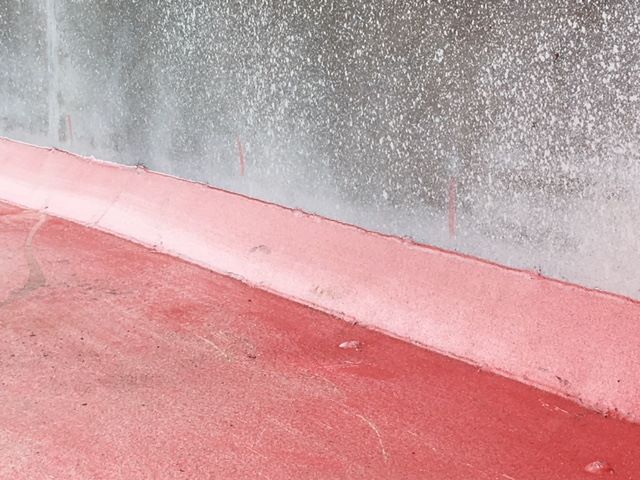 Exterior of a red trailer deck with a reflective wall and concrete barrier, showing a wet surface.