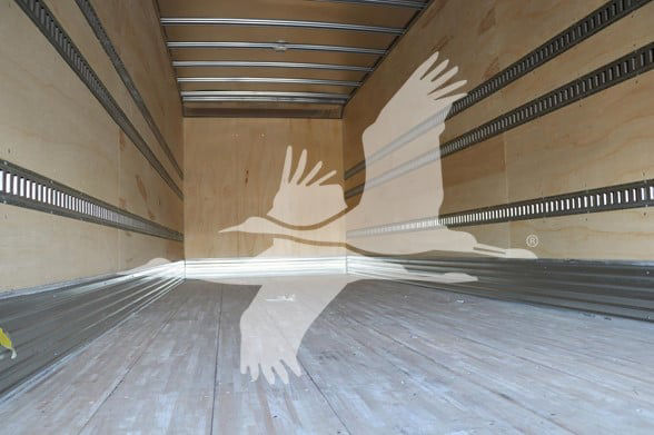 Truck trailer interior with wooden side walls and metal floor; there is a watermark of two white birds crossing.