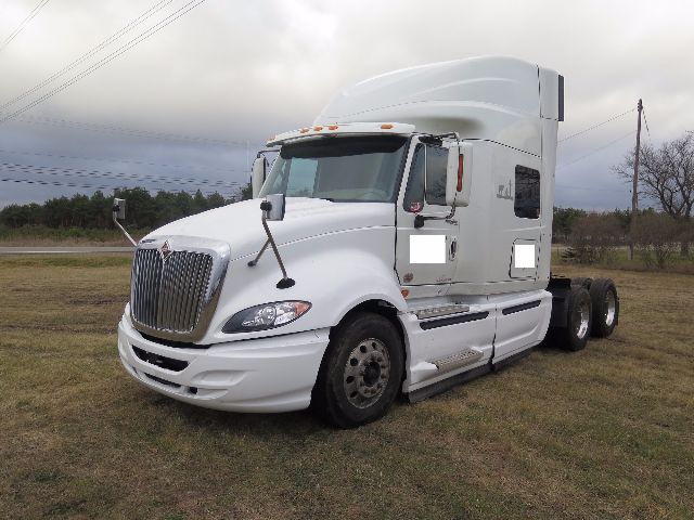 white 2010 International ProStar semi-truck cab with sleeper, front grille, and dual rear axles parked on grass.
