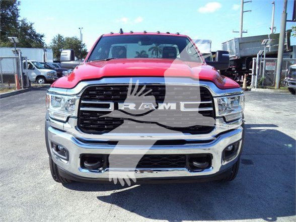 Front view of a red 2024 Ram 5500 SLT truck parked outdoors, showing large chrome grille with RAM logo, bumper, headlights, and front fenders.