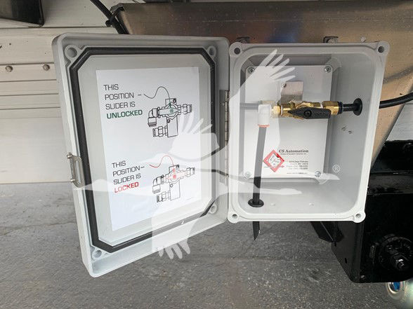Trailer hitch area showing an open control box with a lever/valve and electrical connector. Diagram label reads 'THIS POSITION SLIDER IS UNLOCKED' and 'LOCKED' with illustrations.