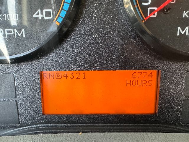 Dashboard display of a 2014 International 7500 showing hours and odometer reading: RN64321 6774 HOURS with orange LCD screen.