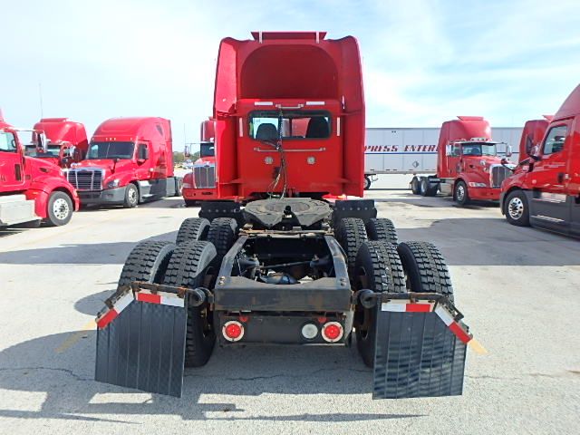 Rear view of a red Peterbilt 386 daycab tractor showing dual rear axles with fifth wheel, mud flaps, and twin fuel/tank areas.
