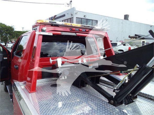 Ram 5500 tow truck bed with hydraulic lift and red cab, rear view showing diamond-plate bed and equipment rigging.