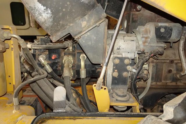 VM106D truck engine bay showing hydraulic lines, control levers, and powertrain components