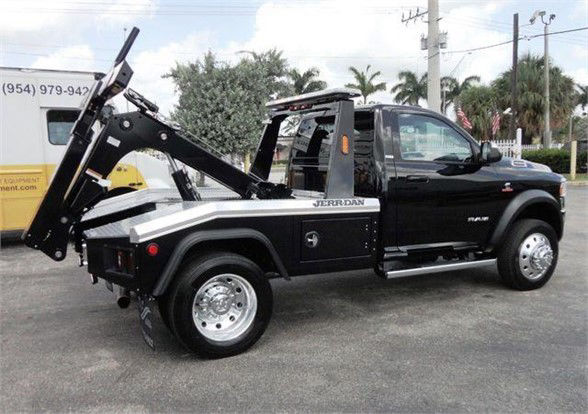 Ram 4500 tow truck with gooseneck tuner in rear, black and white body, JERR-DAN branding visible, side steps, dual rear wheels, towing equipment raised.