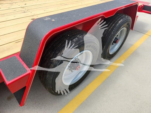 Trailer tandem axle with black tires and white rims, red fender and deck, textured mudflaps, in-service label not visible.