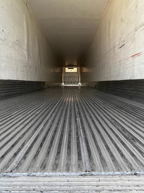 Rear interior of a CIMC Cool Globe trailer with ribbed metal floor and white walls; open end shows exterior light and rear door at far end.