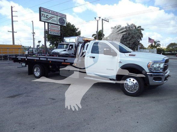 2024 Ram 5500 SLT tow truck with flatbed, white cab, dual rear wheels, dealership lot in background.