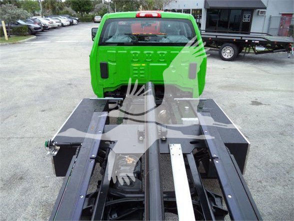 Green 2023 International CV tow truck chassis with flatbed framing and hydraulic components visible from rear view.