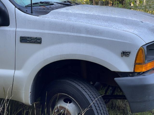 Ford F-450 super duty badge on fender of white dump truck, front wheel visible.