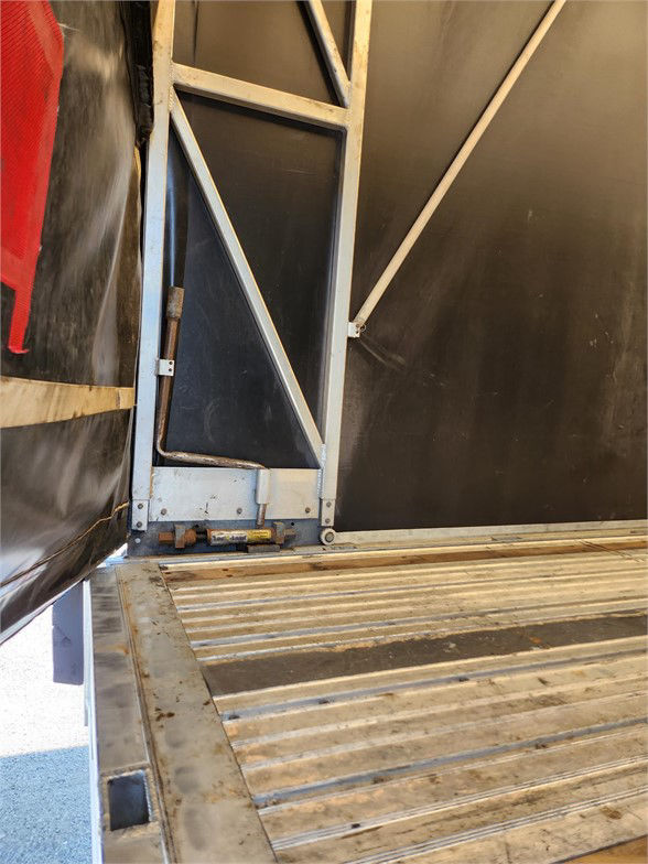 Manac 2020 flatbed trailer cargo area interior with metal framing and ribbed aluminum floor, side door frame visible.