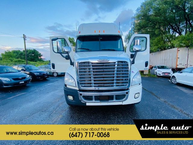 Truck front view showing Freightliner CADCADIA grille, dual open doors, chrome bumper, large windshield, side mirrors.