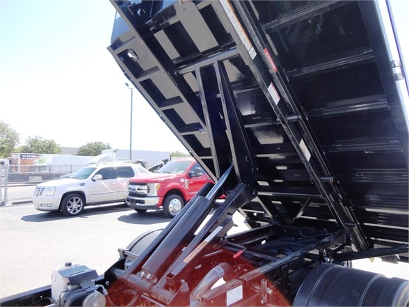 Ram 5500 HD hooklift truck bed raised showing hydraulic cylinders and chassis components.