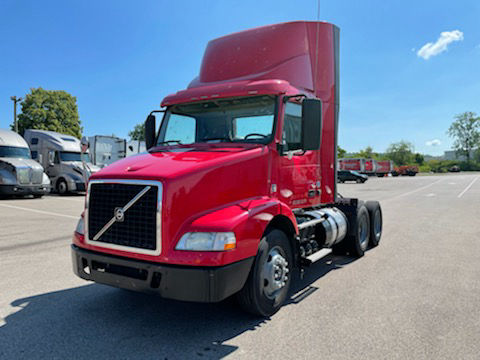 Volvo daytime cab truck in red with tall sleeper, front grille and headlights visible, used convention daycab.
