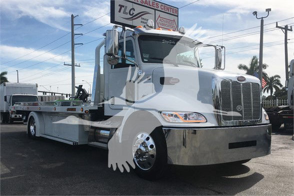 2022 Peterbilt 337 tow truck, white with chrome grille and front bumper, flatbed behind cab, showroom lot in background.