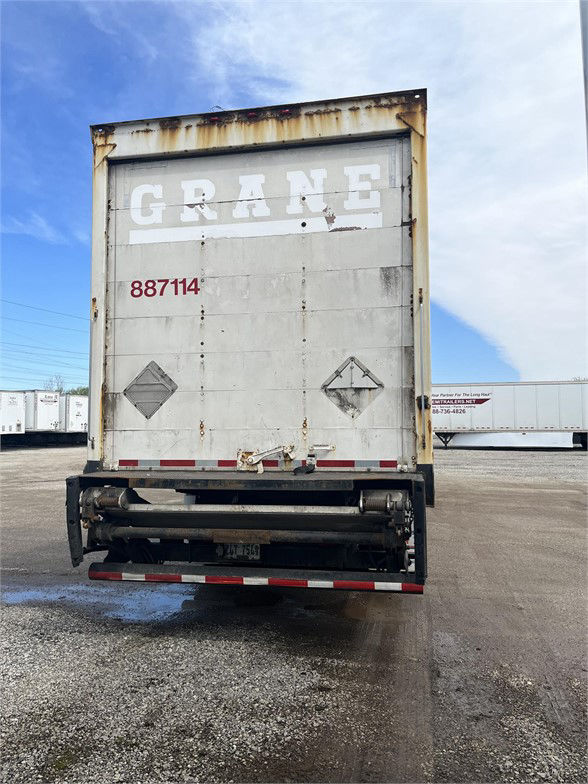 Rear view of a Wabash dry van trailer with faded GRANE text, stock number 887114, rusting door frame, reflective tape, and undercarriage components.