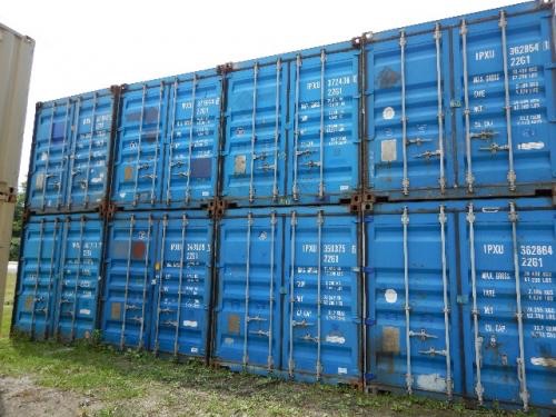 Two rows of stacked blue 20' wind/weather tight shipping containers with white identification codes and locking bars.