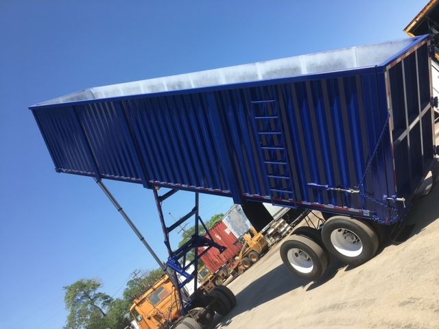 blue 40 ft square dump trailer with dual rear wheels and raised tailgate, side rails and ladder visible.