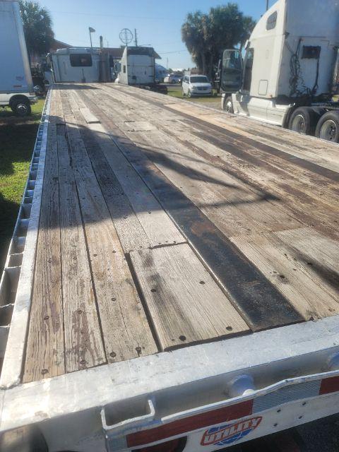 Flatbed trailer deck with weathered wooden planks, metallic side rails, and wheel area visible in background.