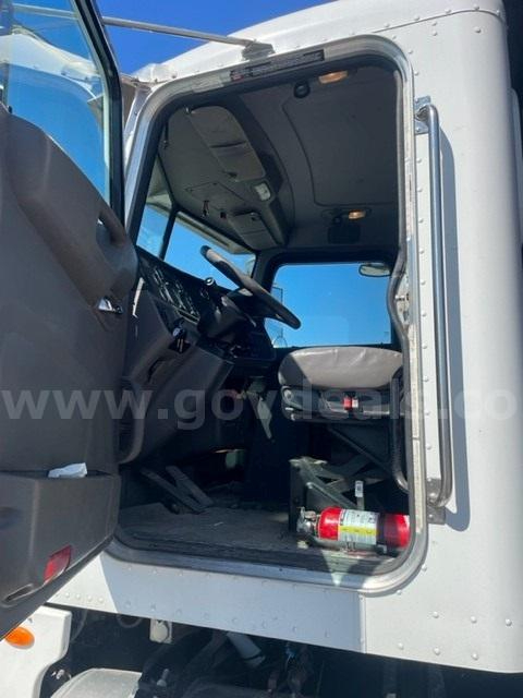 Truck cabin interior of a 2012 Peterbilt 365 with open passenger door, steering wheel, dashboard, and a fire extinguisher visible on the floor.