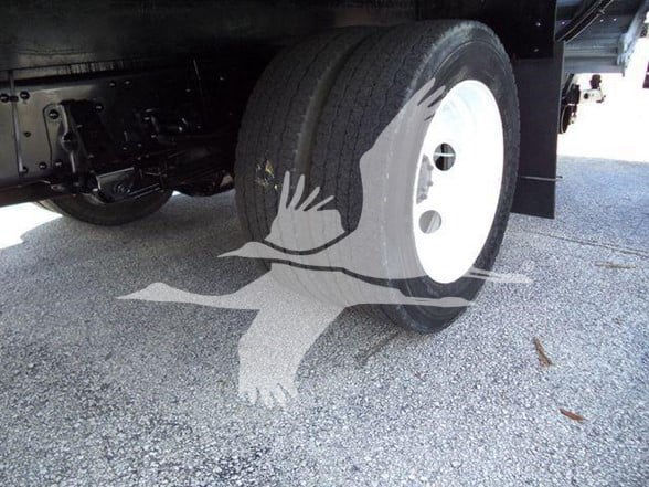 Isuzu NPR HD wheel and undercarriage showing front dual rear wheels, white wheel with black tire, and chassis components.