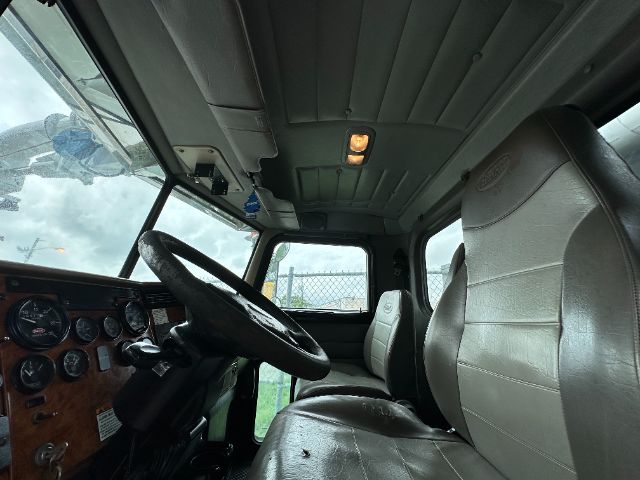 Truck cabin interior of a 2008 Peterbilt 340 showing steering wheel, dashboard with gauges, driver and passenger seats, and overhead console.