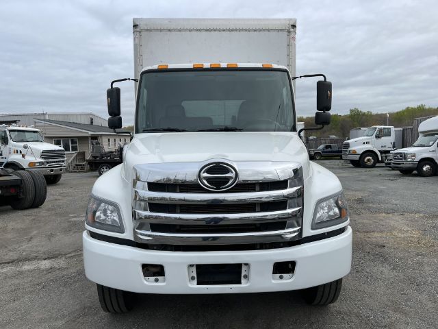 Front view of a white 2017 Hino 268 box truck showing chrome grille, Hino emblem, large rectangular headlights, side mirrors, and box cargo area.
