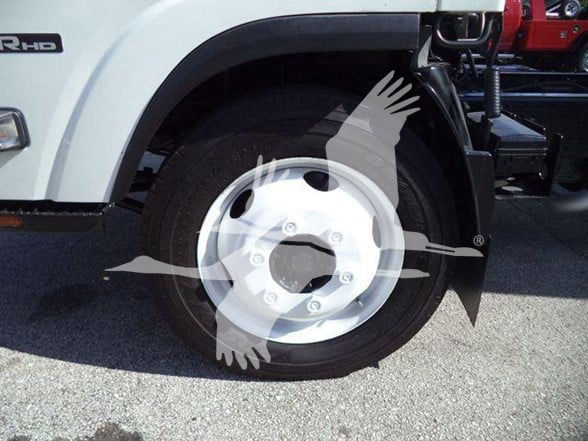 Isuzu NPR HD front wheel and fender showing wheel cover and tire, with 'RHD' badge on the side and part of the chassis visible.