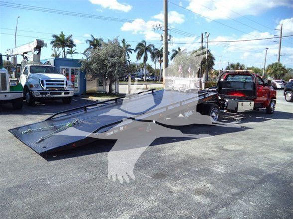 Tow truck trailer and Chevrolet Silverado 6500HD in a dealership lot.